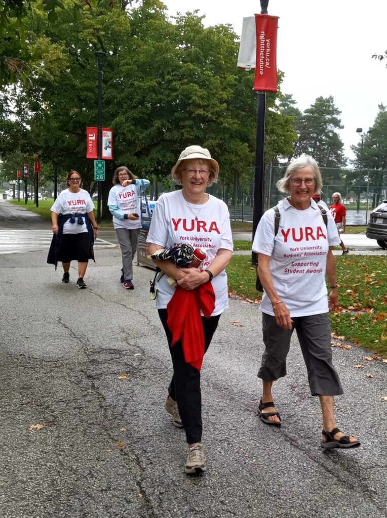 Diane Woody and Gwyn Buck walking near Founders College, with Debbie Hansen and Donna Smith a few feet behind them.